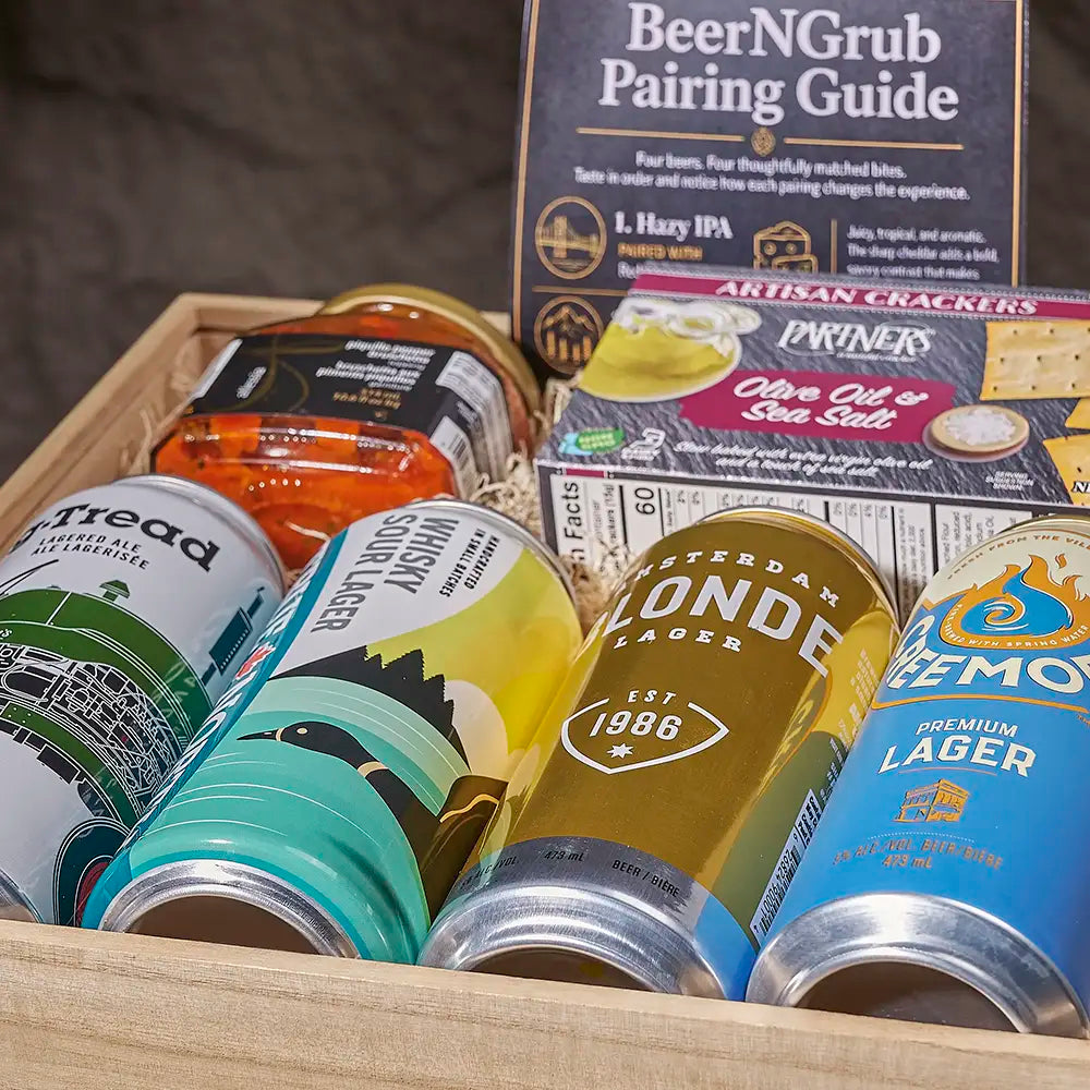 A wooden gift box filled with assorted beer cans, a 'BeerNGrub Pairing Guide' booklet, and an artisanal cracker box. Visible beer brands on the cans include AltTread, Witster, Amsterdam Blonde Lader, and Pilsner.