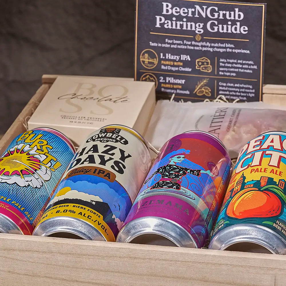 A wooden gift box containing four colorful beer cans, a beige chocolate box, and a standing 'BeerNGrub Pairing Guide' card. The beer cans feature vibrant, illustrated labels in blue, yellow, purple, and green.