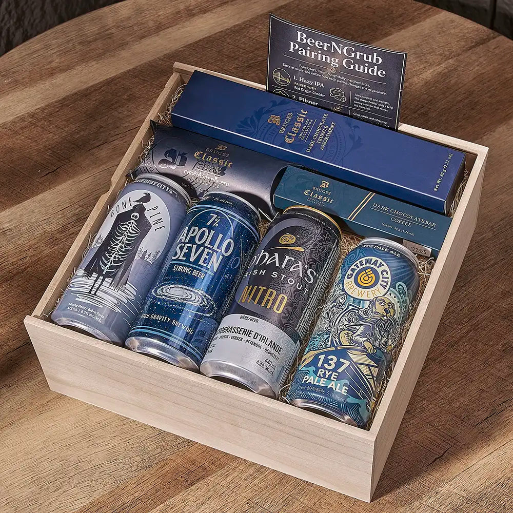 A wooden gift box containing four craft beer cans, a blue book titled 'BeerNGrub Pairing Guide,' and a blue box, arranged on a wooden table.
