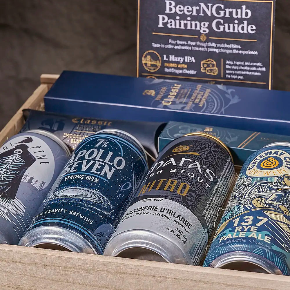 A curated beer gift box featuring multiple craft beer cans and a 'BeerNGrub Pairing Guide' booklet. Visible cans include L'Apollon Seven Strong Ale, Matab's Nutro Stout, and 137 Rye Pale Ale, arranged in a wooden tray with blue branded boxes behind them.
