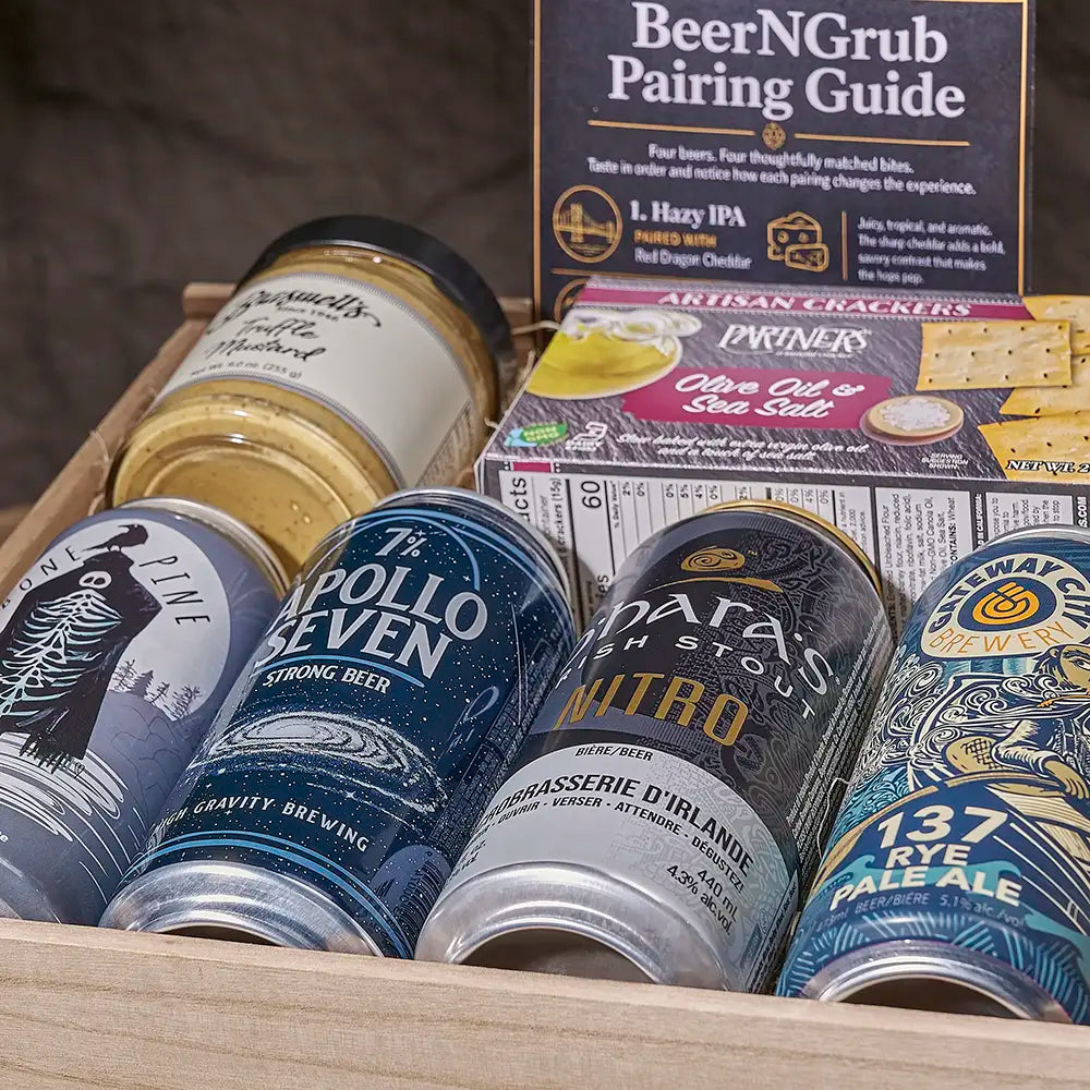 A wooden gift tray filled with assorted beer and snack items, including cans of Stella Artoisa Pollio Seven, Anheuser-Busch InStyle 137 Rye Pale Ale, and Krupsen's Nitro, alongside a BeerNGrub pairing guide and Pariners Olive Oil & Cracker box.